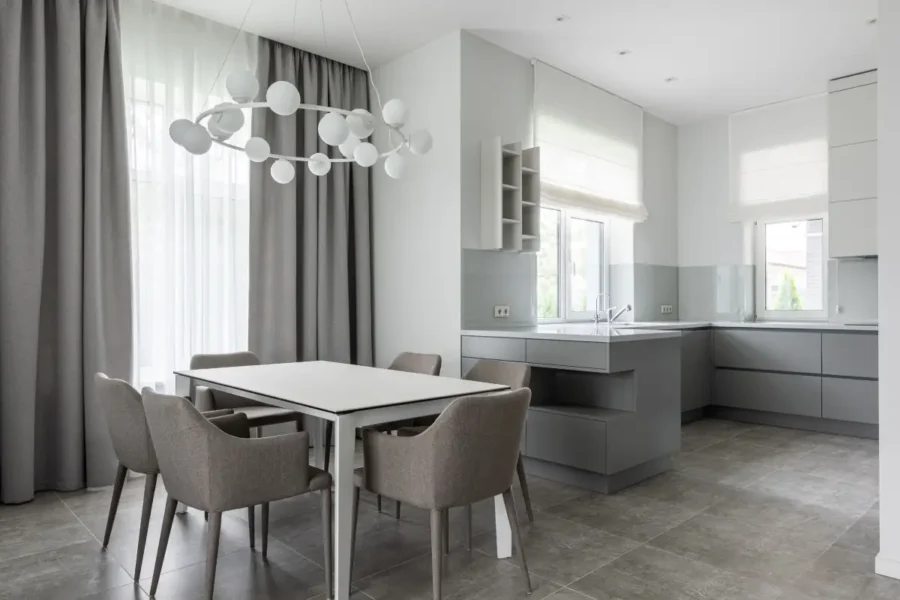 Modern kitchen with Roman shades paired with drapery over dining area windows.